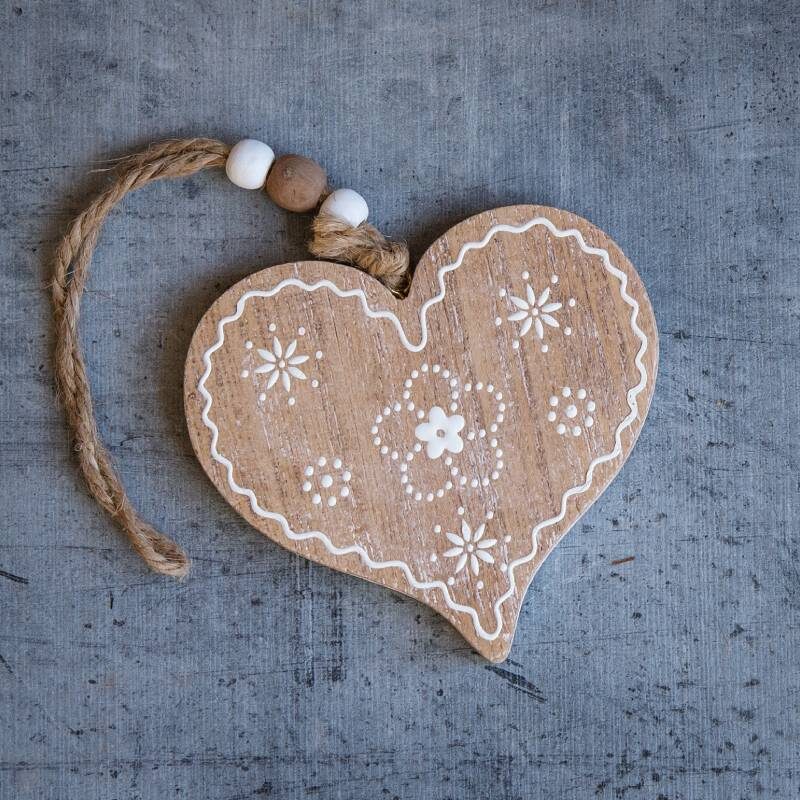 A wooden heart with white designs on it.