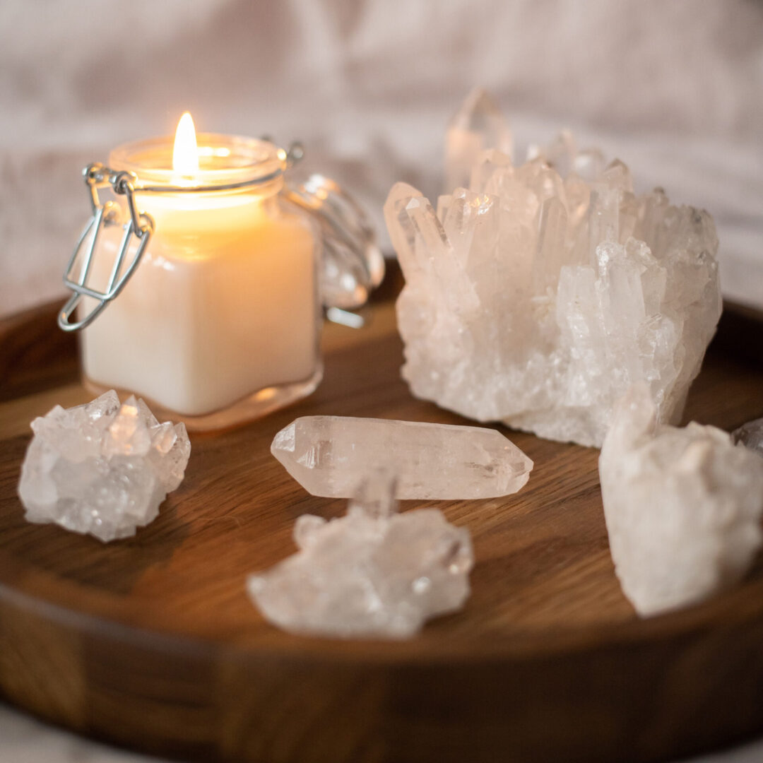 A candle and some white rocks on a wooden tray